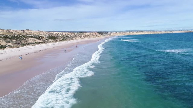 waves rolling in on Port Willunga Beach as people walk along the sand, Adelaide South Australia.