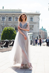 Fototapeta premium Young beautiful brunette woman in dress walking on the street