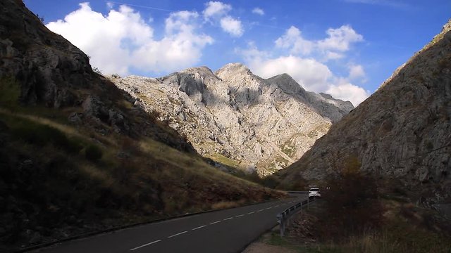  Carretera con curvas entre monta&ntilde;as con coche blanco que pasa y se aleja
