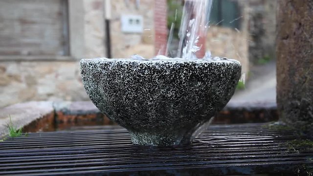 Agua de Fuente cayendo sobre una Taza de Piedra