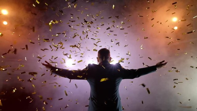 Successful businessman with arms up celebrating his victory. Celebrating success. angle view of excited young men keeping arms raised and expressing positivity while stands on the stage, slow motion