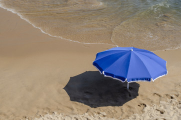 sombrilla azul en la playa a la orilla del mar 