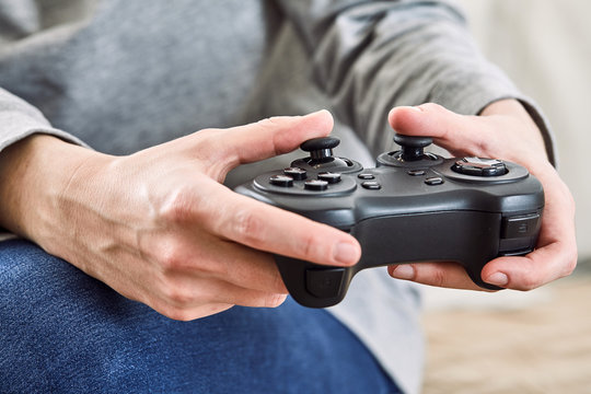 man holding a joystick controllers while playing a video games at home