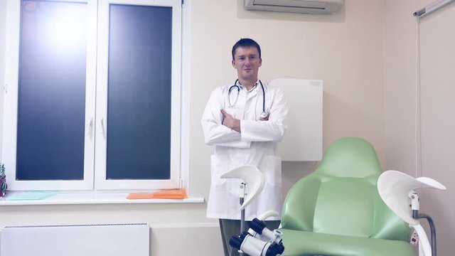 Portrait of a gynecologist in his office near a gynecological chair