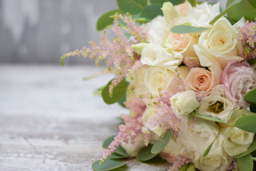 Bridal bouquet. The bride's bouquet. Beautiful bouquet of white, blue, pink flowers and greenery, decorated with long silk ribbon lies on a gray textural background