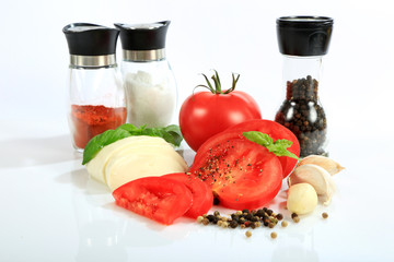 Mozzarella, pomidor, czosnek i bazylia na białym tle, pieprz i sól.