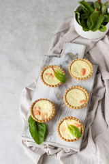 Mini tartlets with cream cheese filling and salmon on white wooden cutting board.