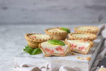 Mini tartlets with cream cheese filling and salmon on white wooden cutting board.