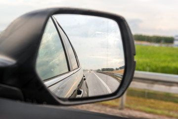 Fototapeta na wymiar Asphalt road reflected in car mirror.