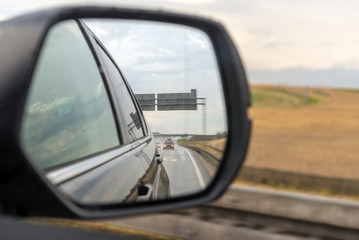Asphalt road reflected in car mirror.