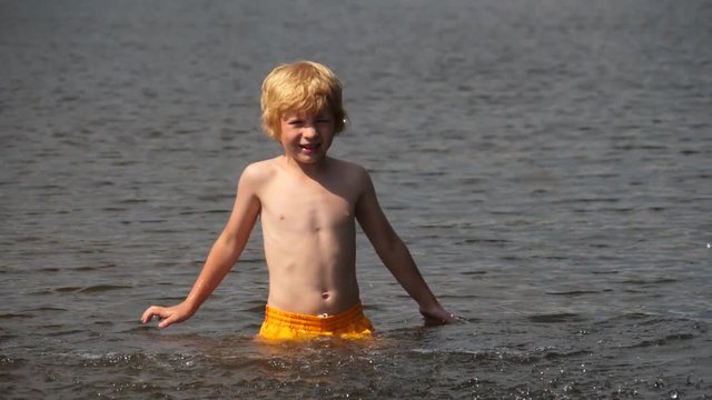 Shirtless Blond Boy Playing in the Water in Summer.