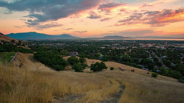 Colorful sunset overlooking Provo from grassy hill looking south across Utah Valley.