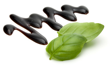 Obraz premium Balsamic vinegar cream and basil leaves isolated on white background. Italian salad dressing, sauce.