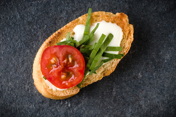 Open faced sandwich canape or crostini on dark stone background closeup. Top view. Vegetarian tartarine.