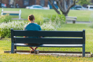 A young man is reading a book on a bench