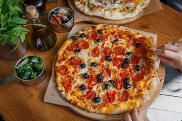 Pizza with pepperoni and olives on restaurant table.