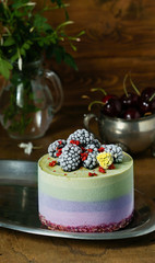 Vegan raw cheesecake with blueberry, cherry, matcha tea, orange,  cashew cream, coconut butter and coconut milk, and base made of almonds, dates  and  dried apricots, oat flakes, lyophilisated berry