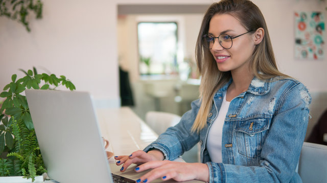picture of freelance woman in glasses works at laptop computer freelance, indoors cafe