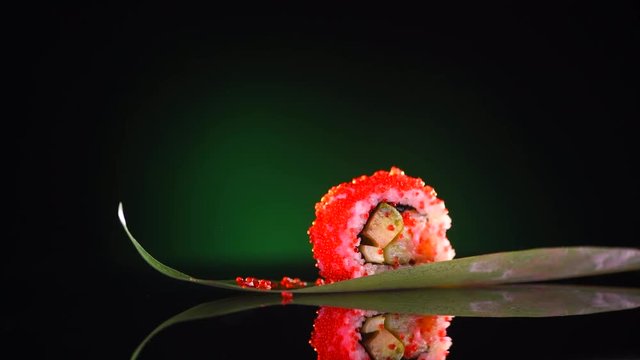 Sushi roll rotated on black background. Sushi roll set with salmon, vegetables, flying fish caviar closeup. Japan restaurant menu. 4K UHD video footage. 3840X2160