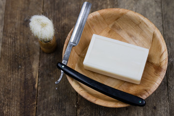 Razor, brush and soap on an old wooden table. Accessories for daily hygiene for men.