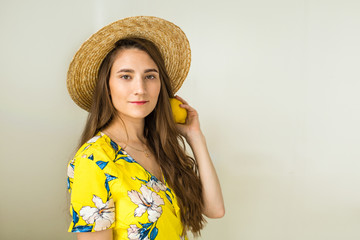 girl in yellow dress and hat holds lemon