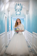 Bride with bouquet of flowers in wonderful blue corridor