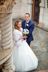 Bride and groom stand together near old column