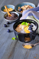 Yogurt with muesli, blueberries, poppy seeds, mint and crushed cornflakes served in black shiny bowl