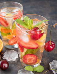 The glasses of lemon water. Lemonade with strawberry, mint and ice on a table. Sunny summer day. Copy spase