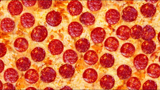 A video of the background pepperoni pizza on a wooden table. Footage. 