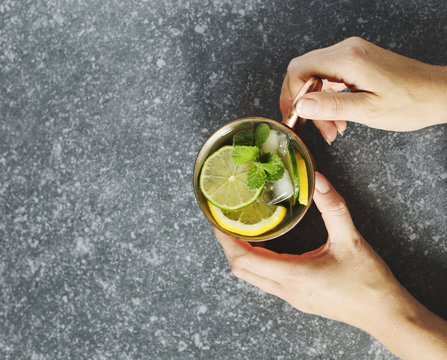 Woman's hands  holding a copper mug of lemonade with fresh mint