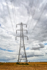 Large electricity pylon with pylons in the distance in a field of corn stubble