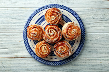 Plate with apple roses from puff pastry on wooden background