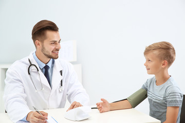 Doctor checking little boy's pulse in hospital