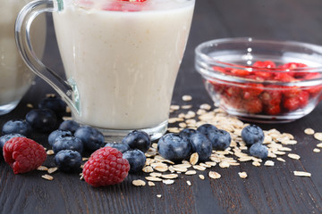 homemade healthy oat smoothie  with berries on rustic wooden background