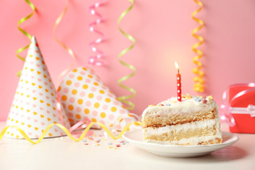 Slice of delicious birthday cake with candle on table