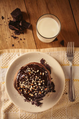 A view of delicious cocoa pancakes with dark chocolate and powdered sugar on a wooden table