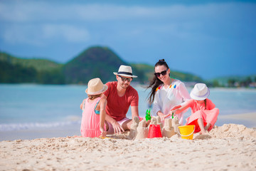 Family making sand castle on white beach on summer holidays
