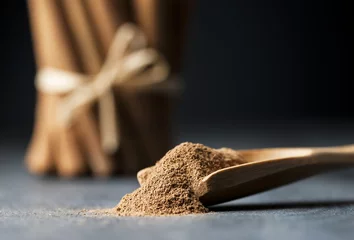 Crédence de cuisine en verre imprimé Herbes Close up cinnamon sticks and powder healthy spice on black wooden background  