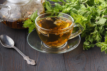 Cup of fresh herbal tea with mint on wooden table. Selective focus