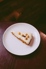 Raw vegan carrot cake with cashew cream layer from above on wooden table. Low key food photography styling concept. 