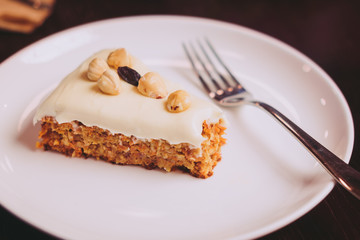 Raw vegan carrot cake with cashew cream layer from above on wooden table. Low key food photography styling concept. 