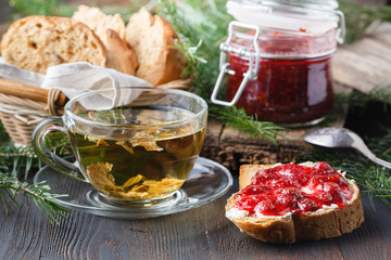 Cup of tea with berry jam on old wooden table