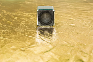 music concept of small gray column louder speaker on yellow reflector background texture with empty...
