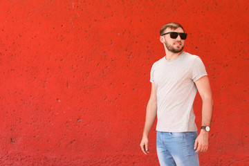 Young man wearing gray t-shirt near color wall on street