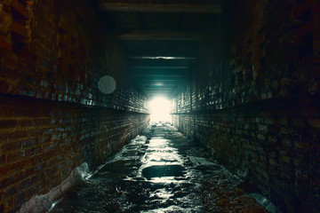 Light and exit in end of dark long brick abandoned industrial tunnel or corridor or sewer channel,...