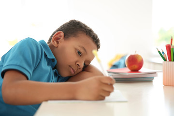 Cute little child doing assignment at desk in classroom. Elementary school