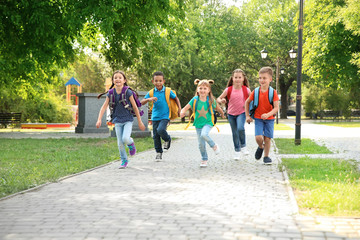 Cute little children with backpacks running outdoors. Elementary school