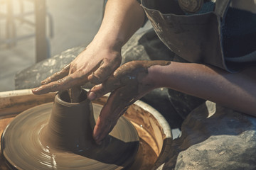 Female potter works with clay on pottery wheel, craftsman hands close up