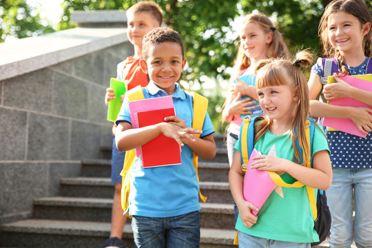 Cute little children with backpacks and notebooks outdoors. Elementary school